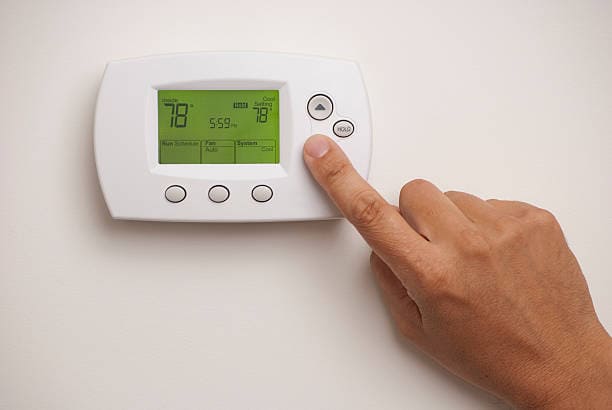 man turning up the temperature on the thermostat